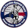 This is the logo for the North Carolina National Guard. It is a circular blue logo with a white border. The center of the logo features a silhouette of a soldier holding a rifle. The background of the logo is the North Carolina state flag. The logo also includes the text “Ready, Reliable, Responsive, Relevant, Always Ready - Ready Team” and “Since 1663”.