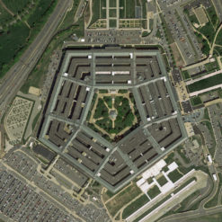 The image presents an aerial view of the Pentagon, the headquarters of the United States Department of Defense, located in Arlington County, Virginia. The Pentagon is a large, five-sided building with a central courtyard. It is surrounded by roads and parking lots. The image, taken from above, provides a detailed view of the building and its immediate surroundings.