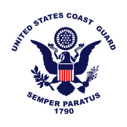 An image of the emblem of the United States Coast Guard. The emblem features a blue shield with a white border, topped by a white eagle with spread wings. The eagle holds a shield with red and white stripes and a blue field with stars. Below the eagle is a banner with the words ‘Semper Paratus’ written in blue. The year ‘1790’ is also written in blue below the banner. The background of the image is white.