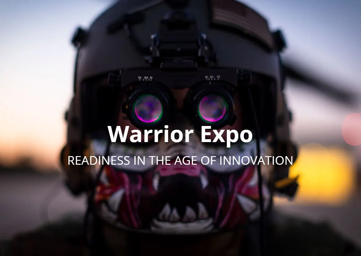 This is a photo-realistic image of a person wearing a black helmet with purple and green night vision goggles against the backdrop of a sunset or sunrise with a purple and orange sky. The text ‘Warrior Expo’ is prominently displayed in white in the center of the image, and the phrase ‘READINESS IN THE AGE OF INNOVATION’ is written in white below it.